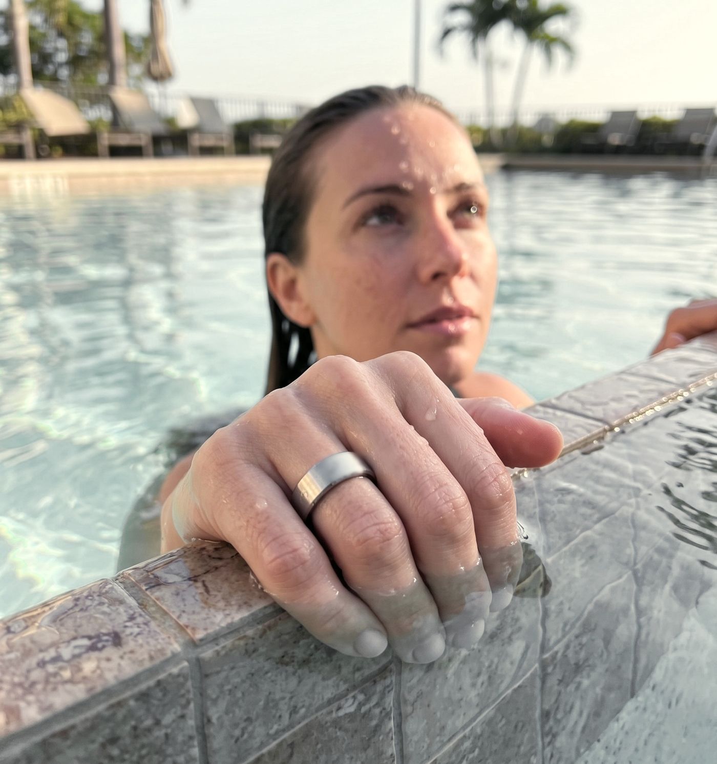 Eine Frau lehnt nach dem Schwimmen entspannt am Beckenrand, am Finger den VYTA Ring in Silber